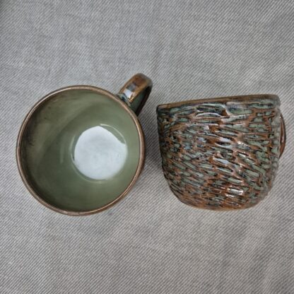 Greenish mug with organic carvings