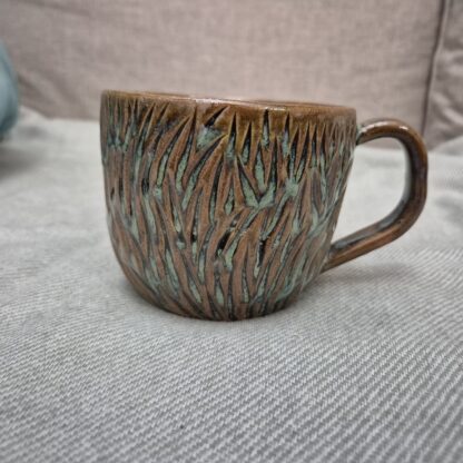 Greenish mug with organic carvings