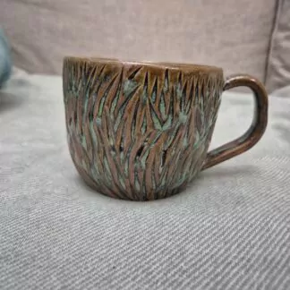 Greenish mug with organic carvings